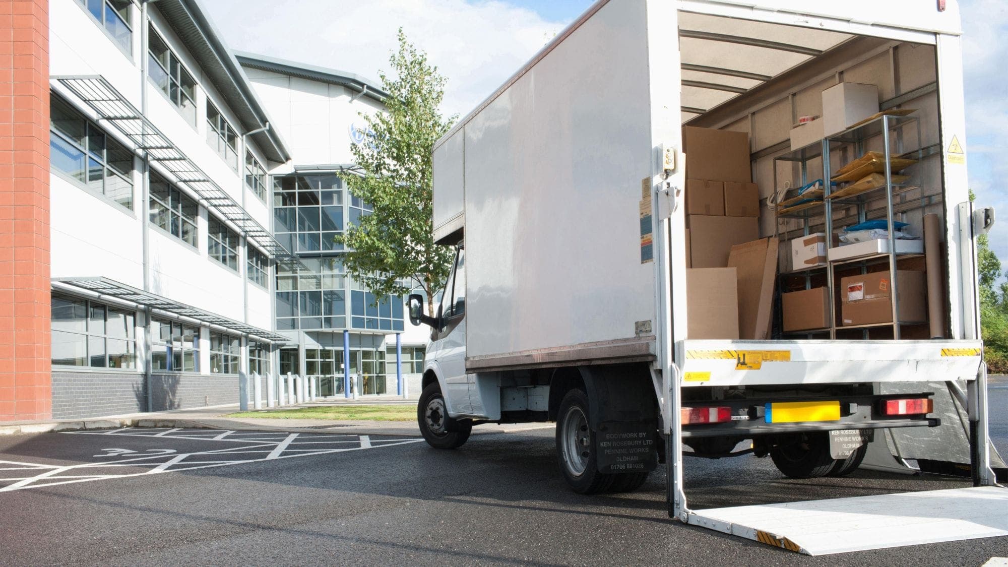 Umzugs-LKW mit Hebebühne und Kartons vor einem Bürogebäude